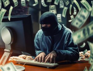 A masked cybercriminal typing on a computer surrounded by floating dollar bills, illustrating the risks of fraud and security breaches in digital lending.