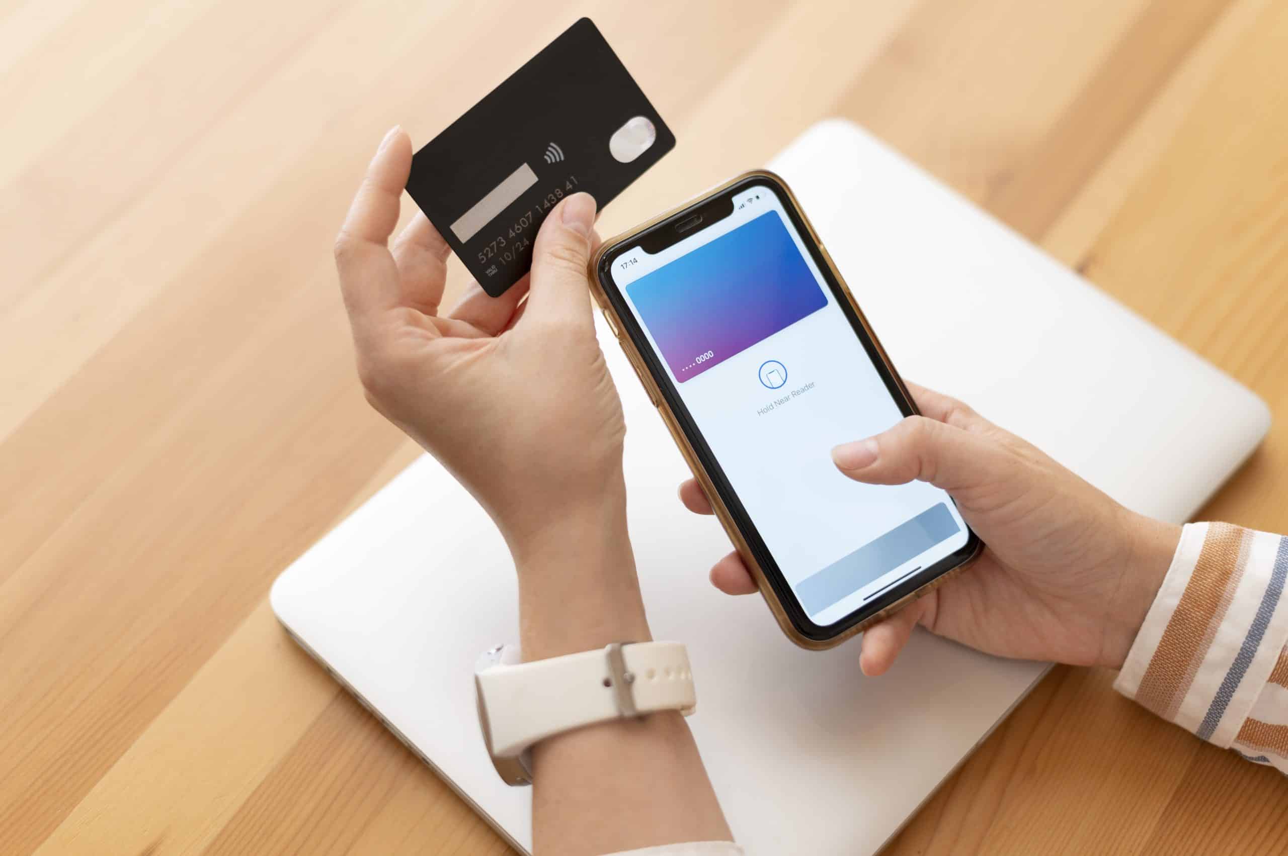 A person holds a black credit card in one hand and a smartphone in the other, with a mobile payment app open on the screen. The setup illustrates the use of mobile credit technology, enabling fast, contactless transactions through digital wallets and smart devices.