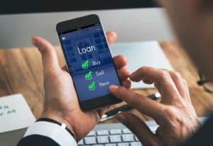 A person using a smartphone to access an app with the word “Loan” on the screen and options to buy, sell, and rent, each marked with a green check. The image illustrates the convenience and accessibility of online loans through mobile devices.