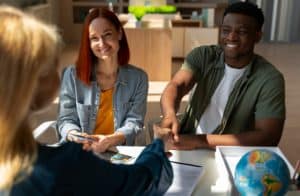 A smiling couple meeting with a financial advisor, shaking hands across a desk, representing trust and personalised services offered by community banks.