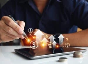 A person using a stylus on a tablet with digital financial icons and upward arrows, symbolising growth and profitability in investment secured loans.