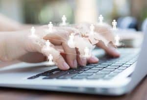 Hands typing on a laptop with a digital network illustration connecting people worldwide, symbolising the global reach and collaboration enabled by crowdlending.