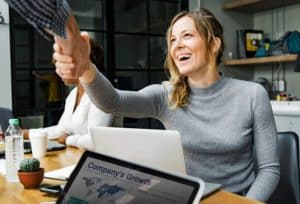 A smiling professional shaking hands during a business meeting, symbolising collaboration, opportunity, and the evolving nature of the gig economy.